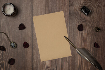 Vintage quill pen and empty old blank paper sheet with old accessories and rose petals on wooden...