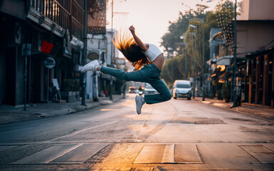 A joyful woman jumping high in the middle of an empty street at sunrise, symbolizing freedom and happiness.