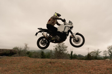 Motorcyclist jumping on adventure tourist enduro motorcycle outdoor on training area