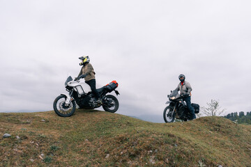 Bikers friends in motorcycle trip on adventure enduro motorcycles in mountains driving off-road