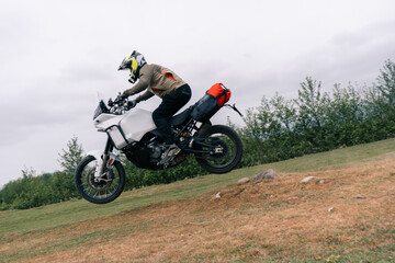 Motorcyclist jumping in moto trip on adventure tourist enduro motorcycle outdoor offroad in mountains