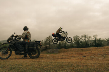Motorcyclist jumping in moto trip with friend on adventure tourist enduro motorcycle outdoor...