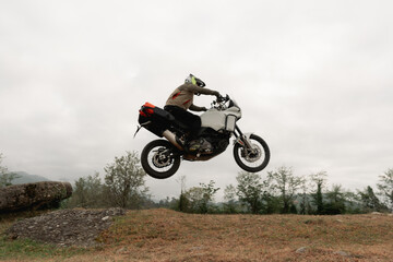 Motorcyclist jumping in moto trip on adventure tourist enduro motorcycle outdoor offroad in...