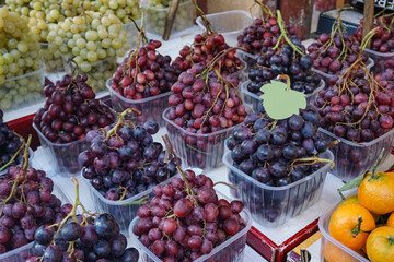 Eye catching display of fresh red, green and purple grapes at a farmers market.