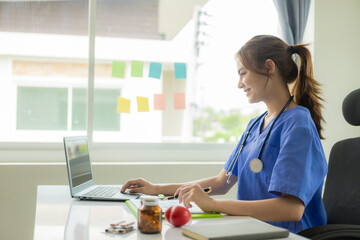 Beautiful young female doctor working with laptop Read electronic medical records Doctors provide online virtual consultations to patients.