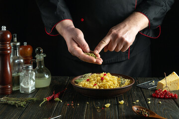 Cooking dinner with pasta and aromatic spices by the hands of a chef on the kitchen table. Italian traditional cuisine cooking concept.