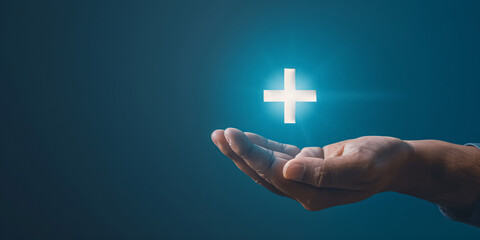 Close up of male hand holding glowing cross on dark background. Medicine and healthcare concept. 