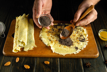 Making pancakes with poppy seeds for lunch. A spoon with poppy seeds in the hands of a chef for...