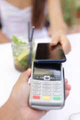Woman is paying for drink with cell phone. Payment concept with NFC technology