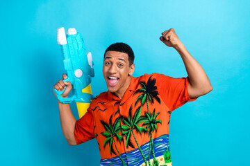 Photo of funky lucky guy dressed print shirt winnning water gun game isolated blue color background