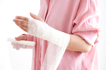 Obraz premium A woman in a pink shirt holds a bandage and puts a bandage on her arm.