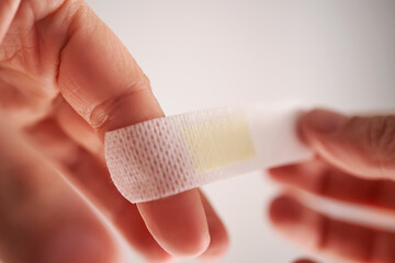 Applying an adhesive plaster to a finger. Close-up.