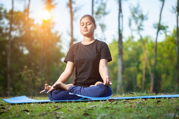 young women sitting in a lotus position practicing apana mudra at forest during sunrise