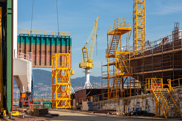 This image captures the bustling activity at an industrial shipyard with large cranes and equipment...