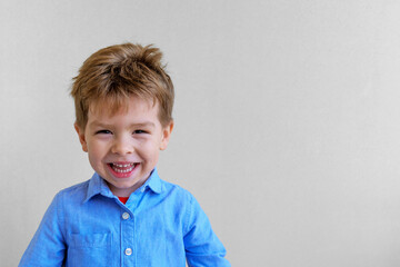 Cute smiling little boy in shirt looking at camera on gray background, copy space