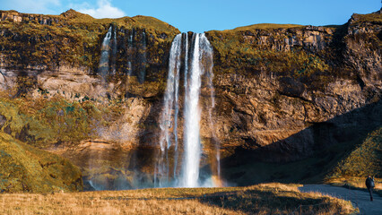 Seljalandsfoss waterfall at sunset. Iceland, huge flow of water 60 meters high. Tourism, nature, wonders, northern lands.
