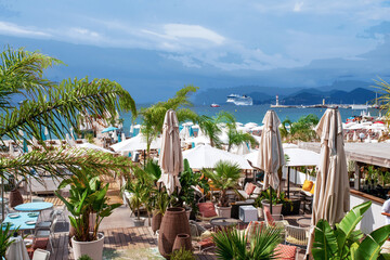 Awe beach in Cannes with potted palm trees , cafe, white awnings and outdoors chairs