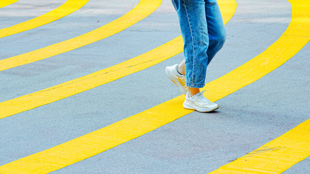 A person walking on a crosswalk with yellow lines.