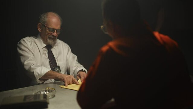 Police detectives interrogating inmate in dark room