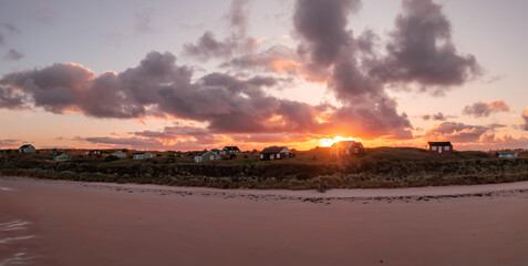 Panoramic view of remote beach huts on the Northumberland coast at Embleton Bay beach at sunrise