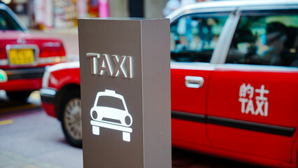 a red taxi parked at a taxi stand with a sign that says 