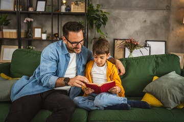 Obraz premium Father and son read a book and have fun while spend time together