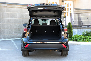 Modern car with open empty trunk outdoors. Black car is ready to load luggage. Clean trunk wagon car. Modern SUV car open trunk. Open back door modern SUV trunk. SUV boot is open.