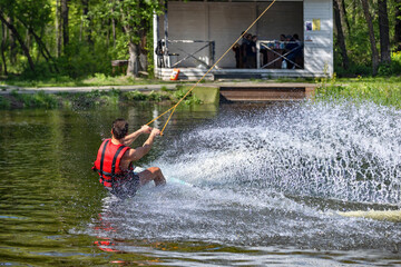Water sport, wakeboarder rides on a water board on a warm spring day, raising beautiful large water splashes.