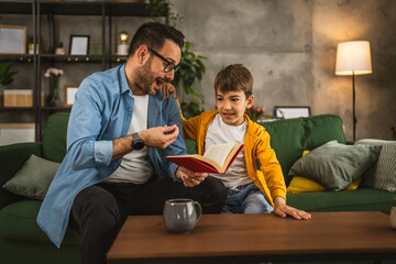 Father and son read a book and have fun while spend time together