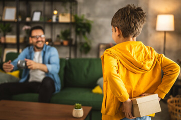 Son hold gift behind back and want to surprise his father for birthday