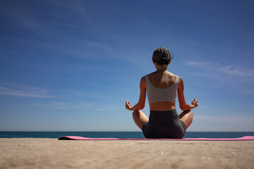 Brunette Woman Meditating on Pink Exercise Mat by the Sea