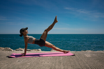 Brunette Woman Performing Isometric Exercises on Pink Exercise Mat by the Sea