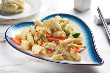 Salad with squid, carrots and cucumber in a plate on the table