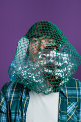 Man's head is ensnared by a green net filled with plastic bottles, symbolizing the suffocating impact of plastic waste on individuals and the environment. 