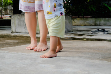 foot of child and mother walking in the park. Child learns to take the first steps in the park. close up leg of infant baby walking on path with mother helping