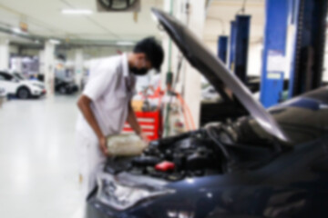 Blurry car repair station and repairman working in the garage. Car maintenance or checking of car repair concept.