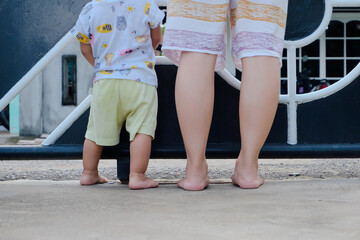 foot of child and mother walking in the park. Child learns to take the first steps in the park. close up leg of infant baby walking on path with mother helping