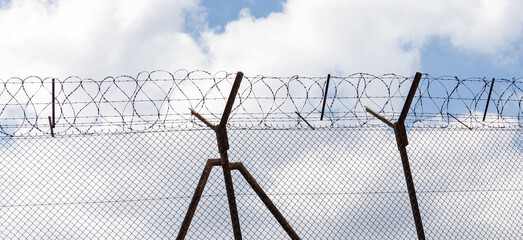 Wire fence with barbed wire. Banner with barbed wire on sky background, prison concept