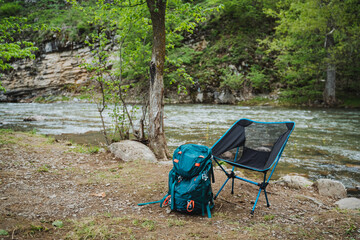 Backpack and chair resting by river in natural landscape