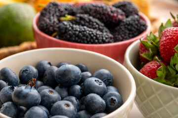 Blueberries, strawberries and black mulberries in bowls