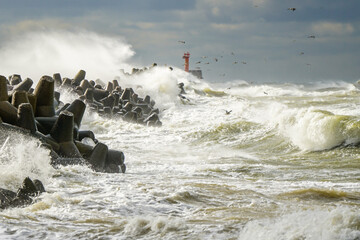 Stormy weather, big waves crashing against the concrete breakwaters of the port with high splashes