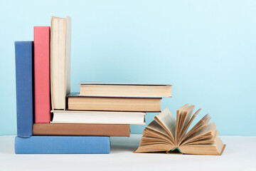 Open book, hardback colorful books on wooden table, blue background. Back to school. Copy space for...