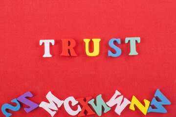 TRUSTword on red background composed from colorful abc alphabet block wooden letters, copy space...