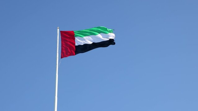 UAE flag waving in the blue sky, national symbol of UAE