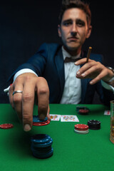 Poker player with cards and chips at green table in casino.