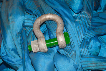 A pile of blue cargo belts with cargo rigging shackle. close-up. Blue slings.