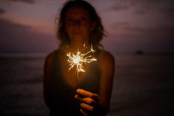 woman holding sparkles celebrating on tropical beach