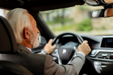 Joyful senior gentleman enjoying a leisurely drive in his modern car on a sunny day