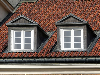 Two symmetrical dormer windows against the background of the tiled roof