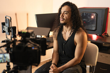 Video Production in a Modern Studio. A long-haired content creator immersed in his studio,...